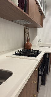 Cozinha planejada com bancada branca em superfície mineral e cooktop a gás