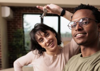 Husband and wife buying new apartment and having house keys, celebrate relationship event being property homeowners. Moving in real estate flat together, bought on mortgage loan.