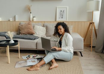 Mulher trabalhando com notebook na sala, representando a importância da moradia na rotina e no bem-estar